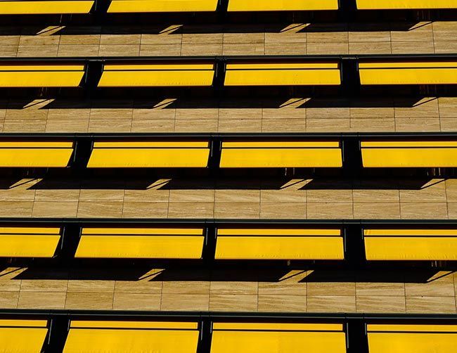 Des auvents jaunes s'étendent depuis un bâtiment beige, projetant des ombres.