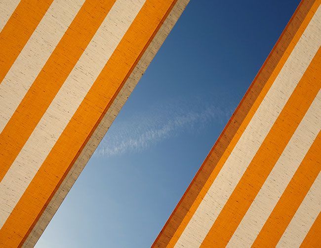 Auvent à rayures jaunes et blanches laissant entrevoir un ciel bleu clair.