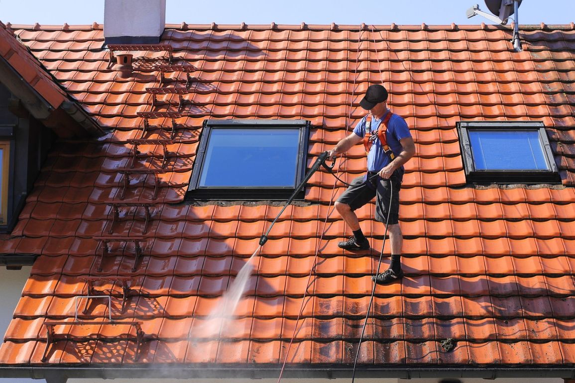 Photo d'un couvreur qui nettoie d'une toiture en tuiles