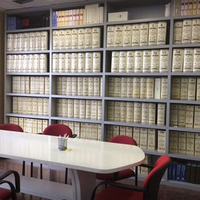 Una habitación con una mesa y sillas rodeada de estantes con libros, incluido uno que dice