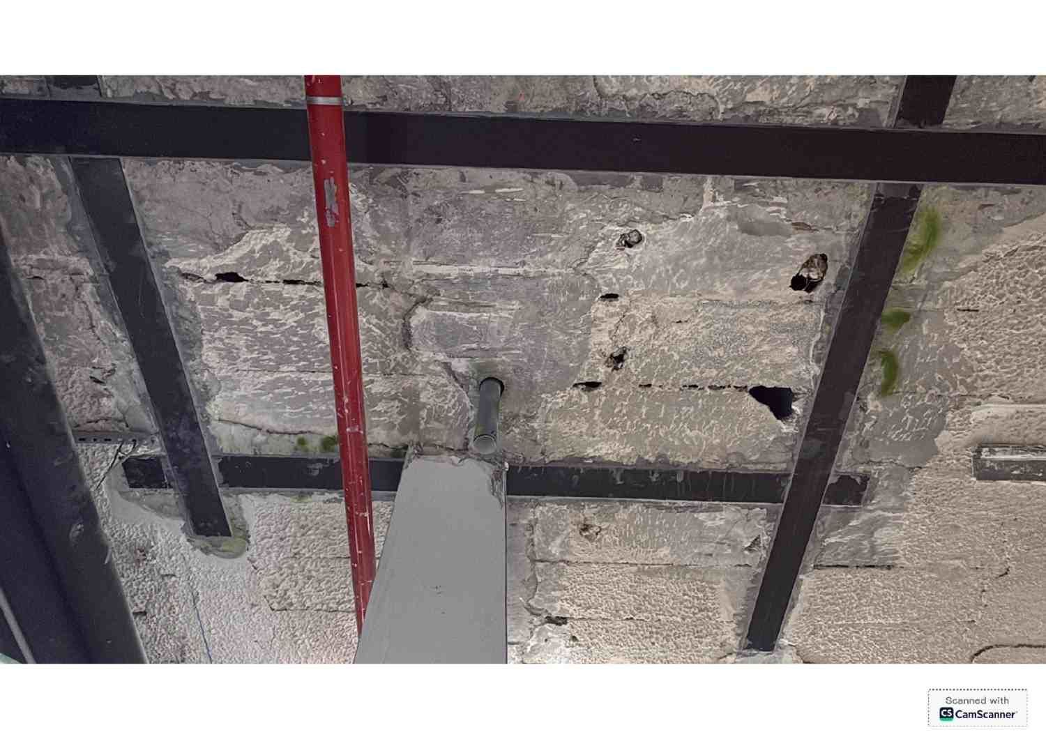 Techo visto con tuberías, cables y paneles aislantes sobre una estructura metálica negra