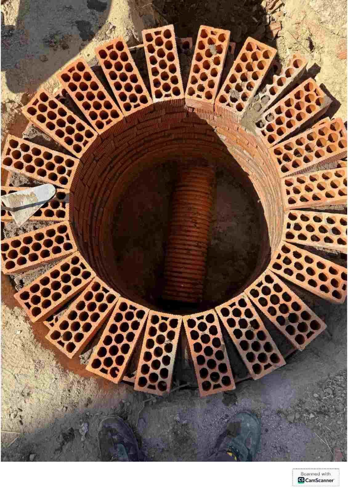 Vista superior de una estructura circular de ladrillo, con ladrillos naranjas perforados alrededor de un orificio central
