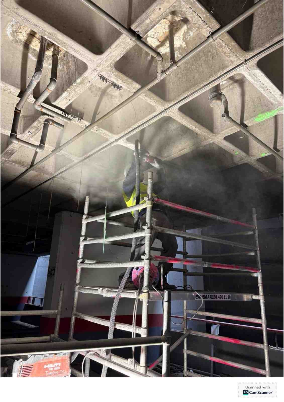 Andamio en una habitación llena de humo, bajo un techo dañado con vigas y tuberías a la vista