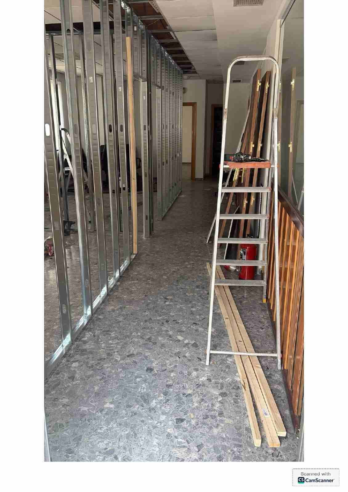 Pasillo en renovación, con la estructura a la vista, una escalera y materiales de construcción en el suelo