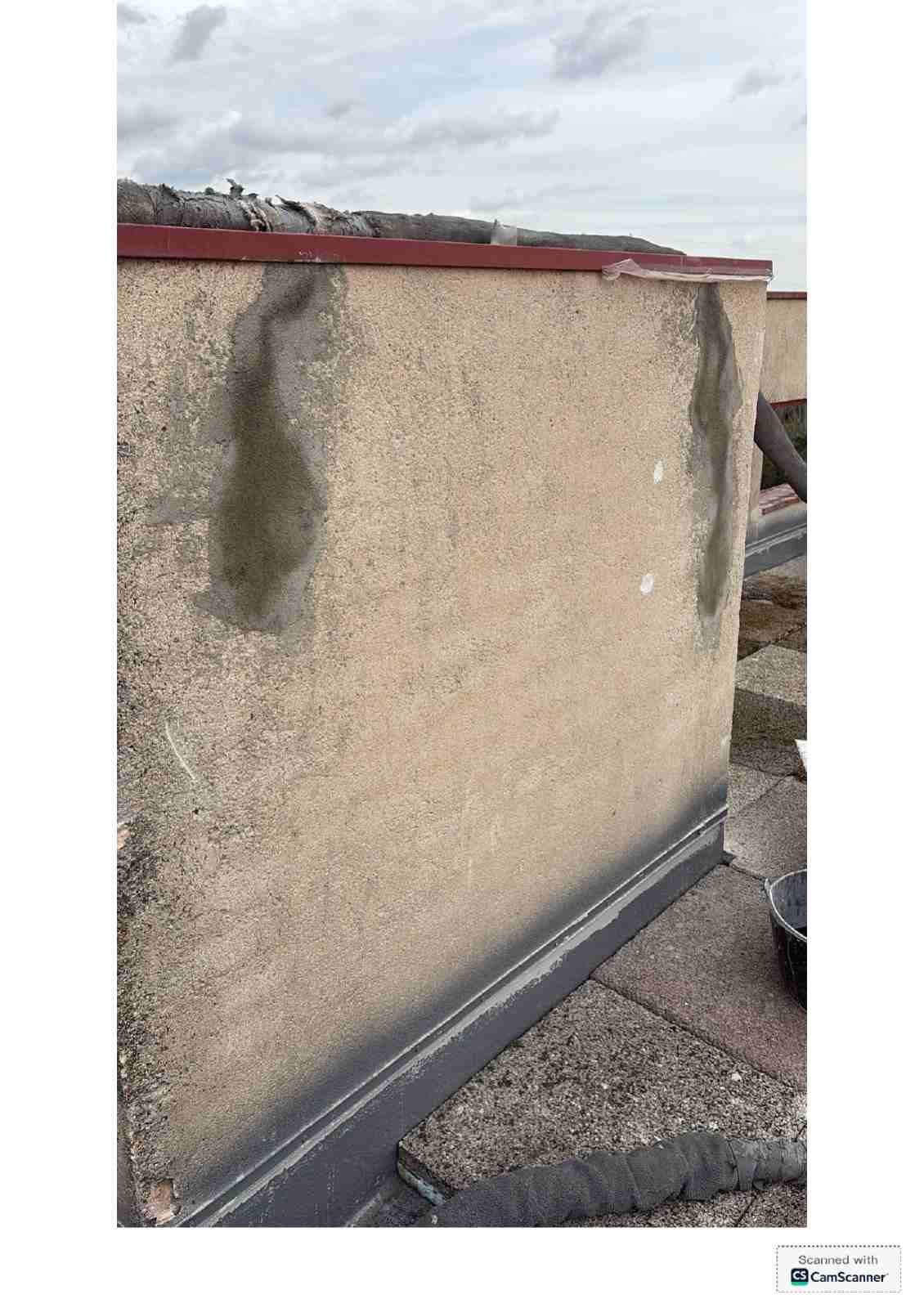 Pared exterior beige desgastada, con una mancha verde oscuro cerca de la parte superior y el borde de un tejado rojo.