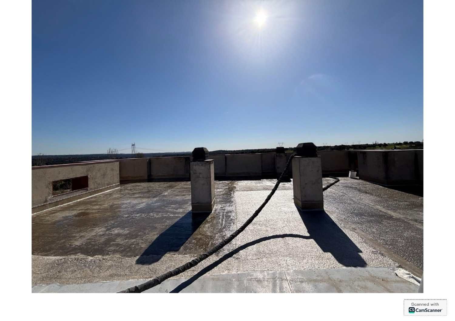 Azotea soleada y plana con dos tubos de ventilación y sombras bajo un cielo azul despejado