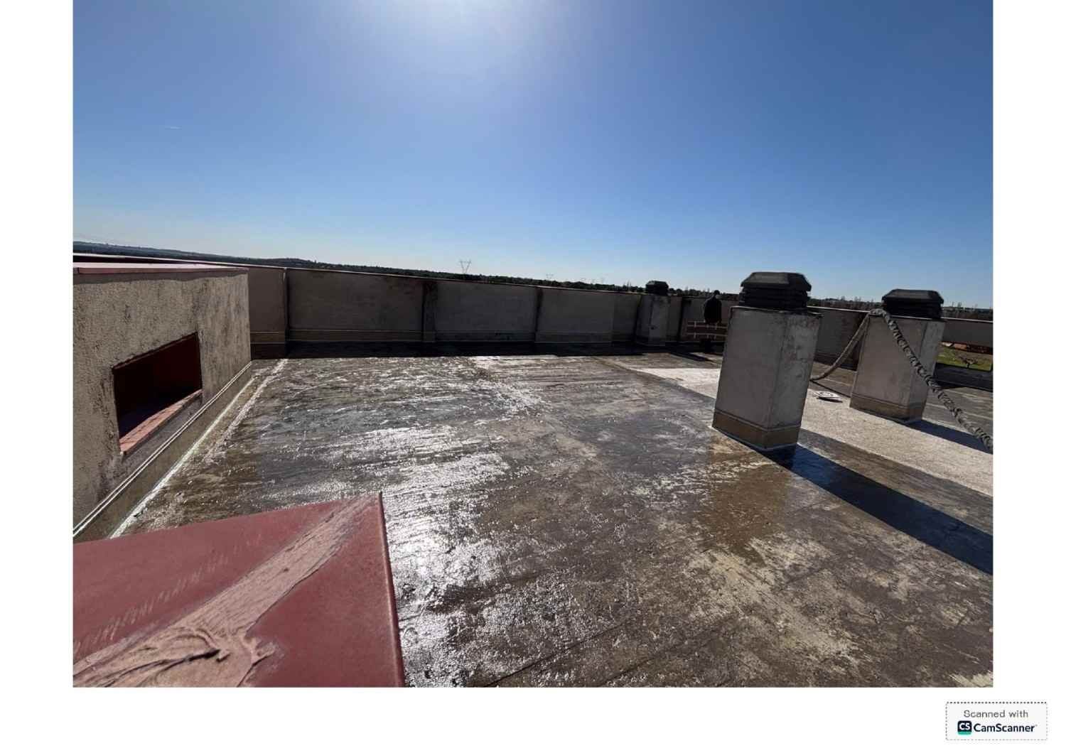 Azotea con una superficie plana y reflectante, muros bajos en el perímetro y un cielo azul despejado encima