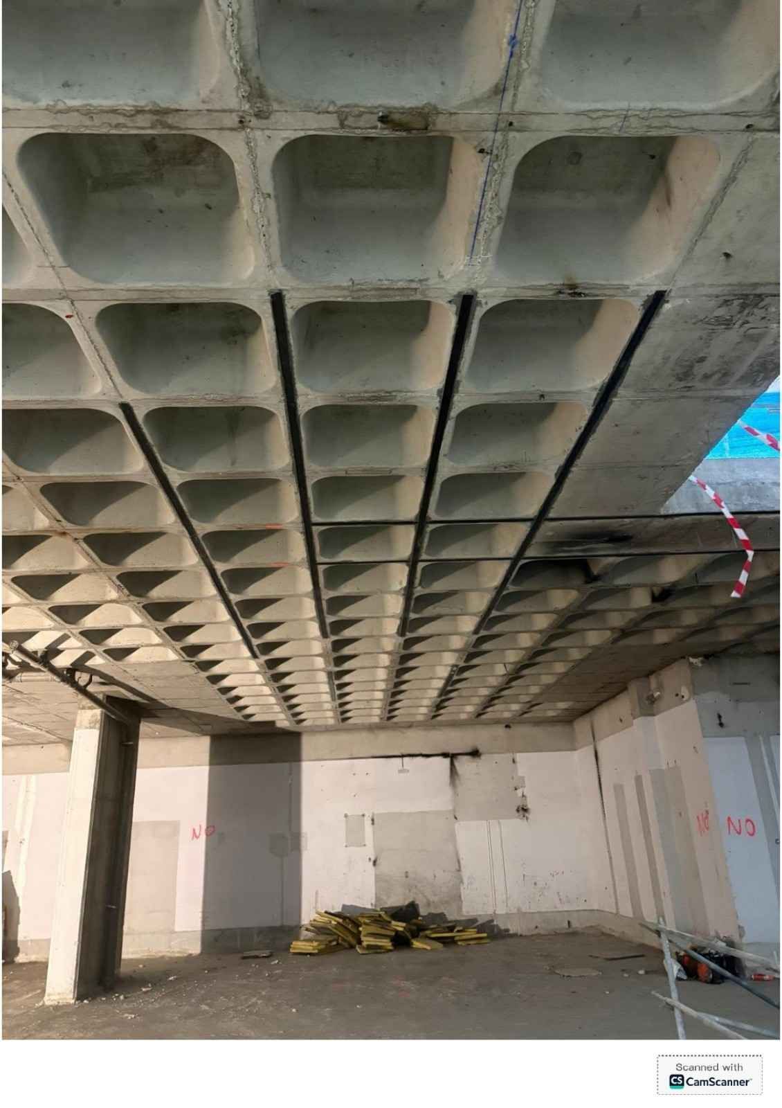 Techo de hormigón dañado con la estructura a la vista en una habitación sin terminar y escombros en el suelo