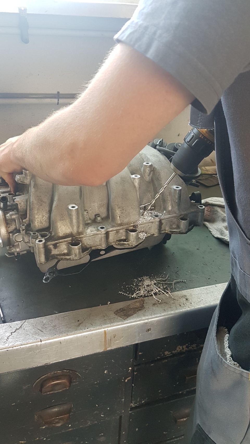 Mechaniker bohrt an ausgebautem Kfzteil