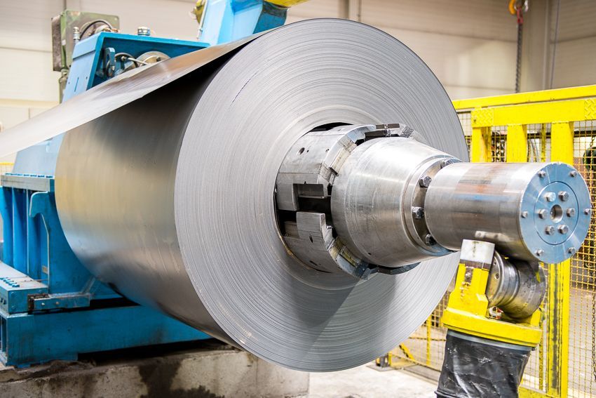 In einer Fabrik wird auf einer Maschine eine große Metallrolle gerollt.