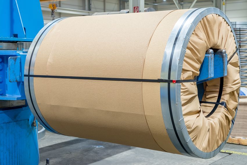 Eine große Papierrolle liegt auf einer Maschine in einer Fabrik
