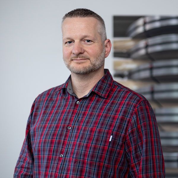 Ein Mann mit Bart trägt ein kariertes Hemd.