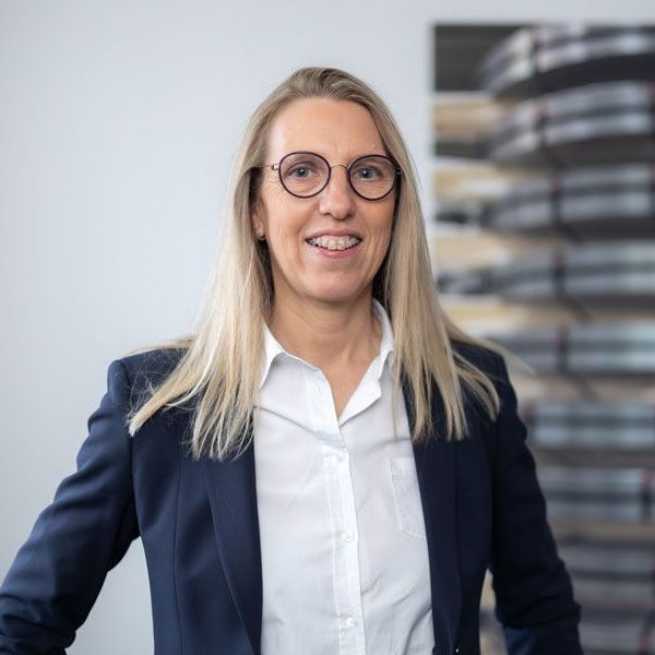 Eine Frau mit Brille und schwarzer Jacke posiert für ein Foto.