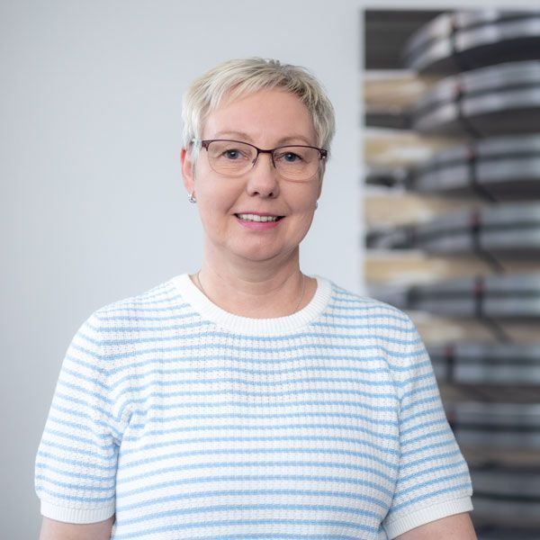 Eine Frau im blauen Pullover lächelt in die Kamera.