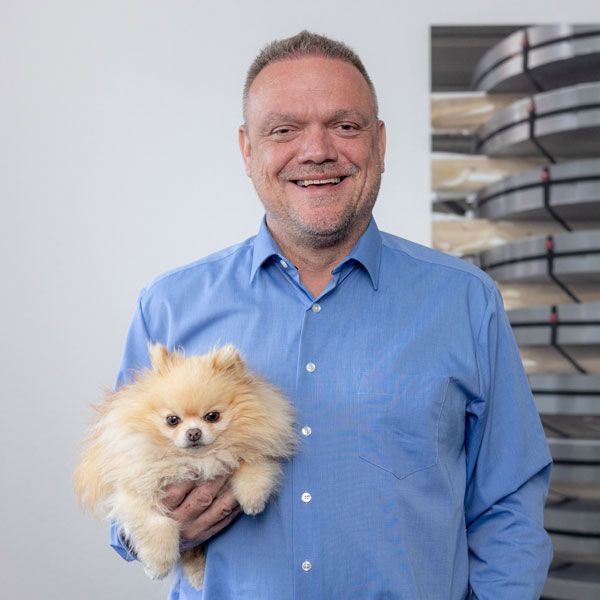 Ein Mann in Anzug und blauem Hemd lächelt in die Kamera.