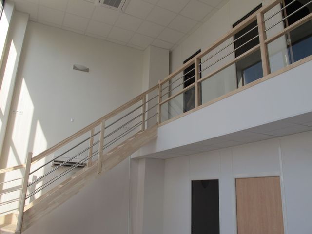 Ouvrier à côté d'une rampe d'escalier avec un rouleau de peinture à la main.
