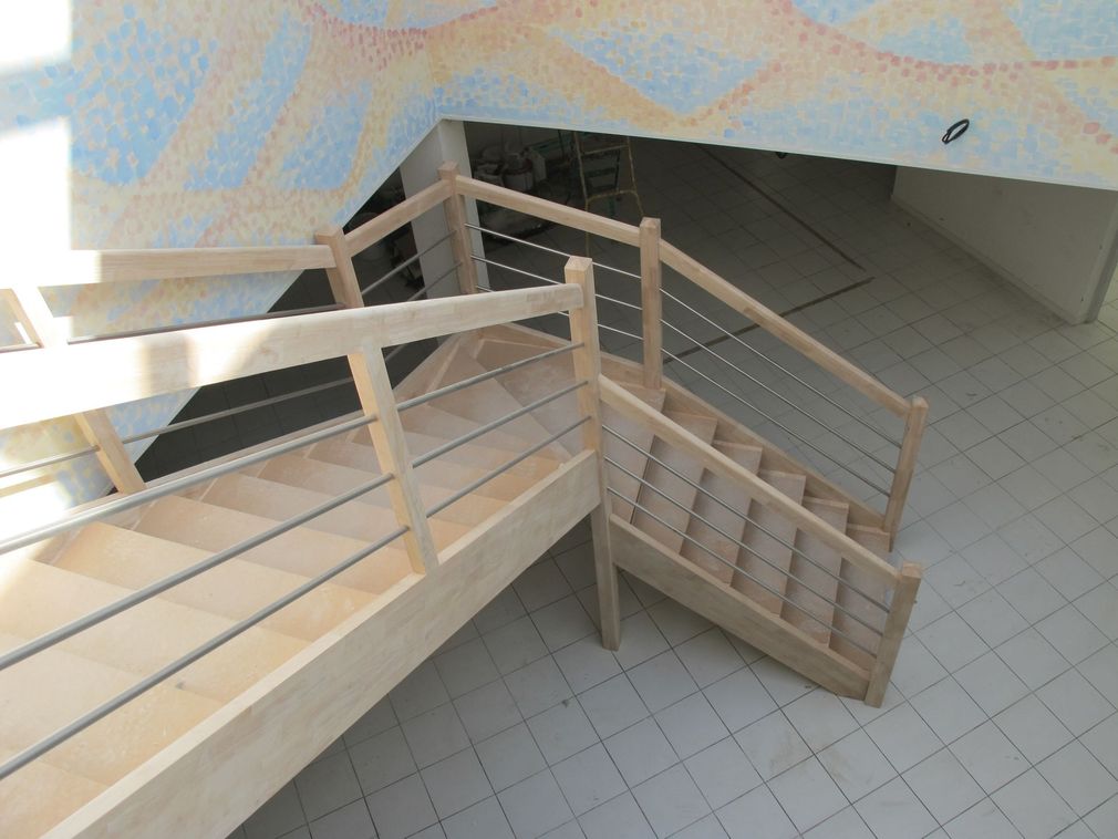 Escalier intérieur avec murs beiges bruts et marches en bois à côté d'une porte