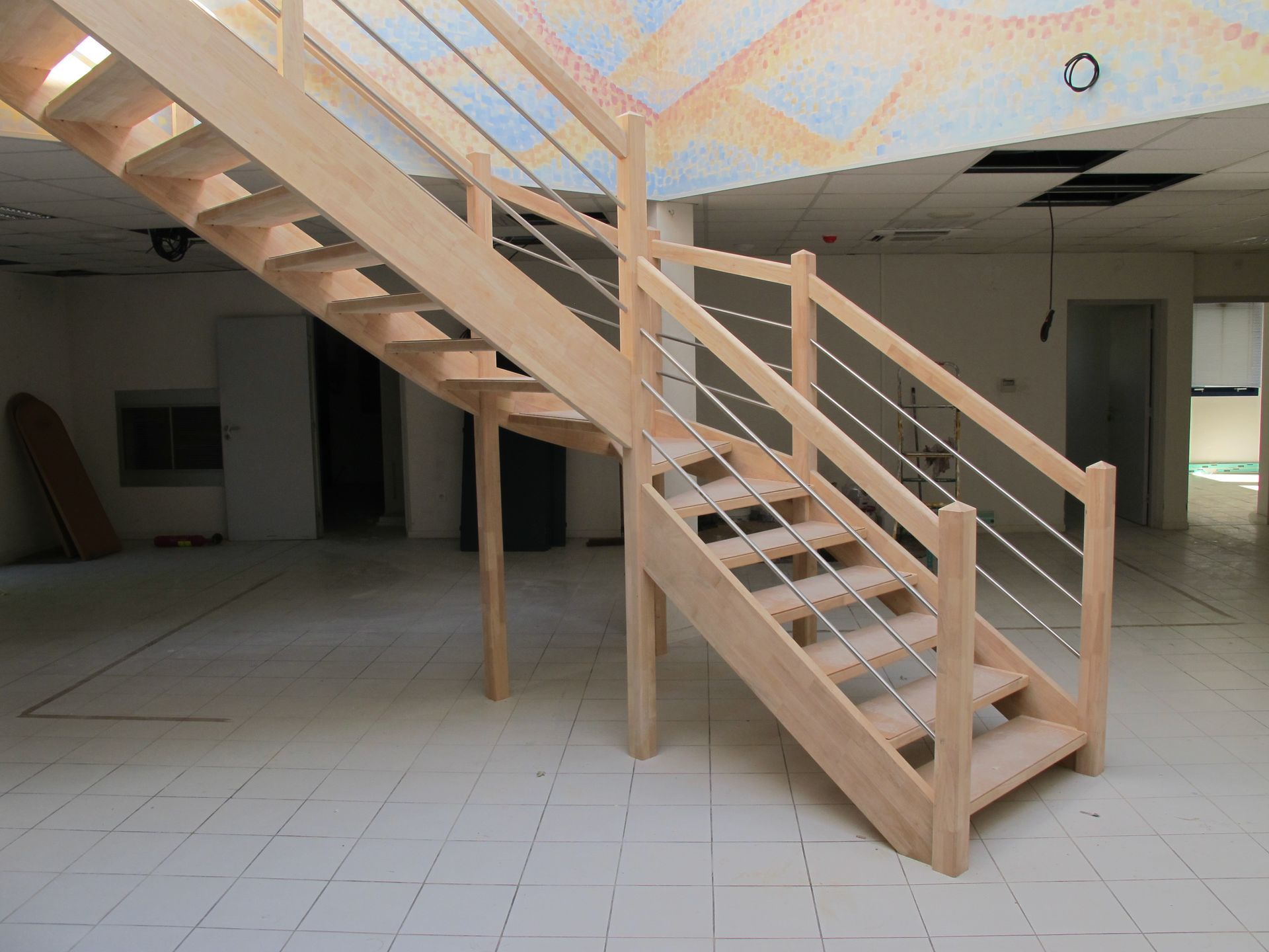 Pièce intérieure avec un escalier en bois menant à un étage supérieur, en construction ou inachevée