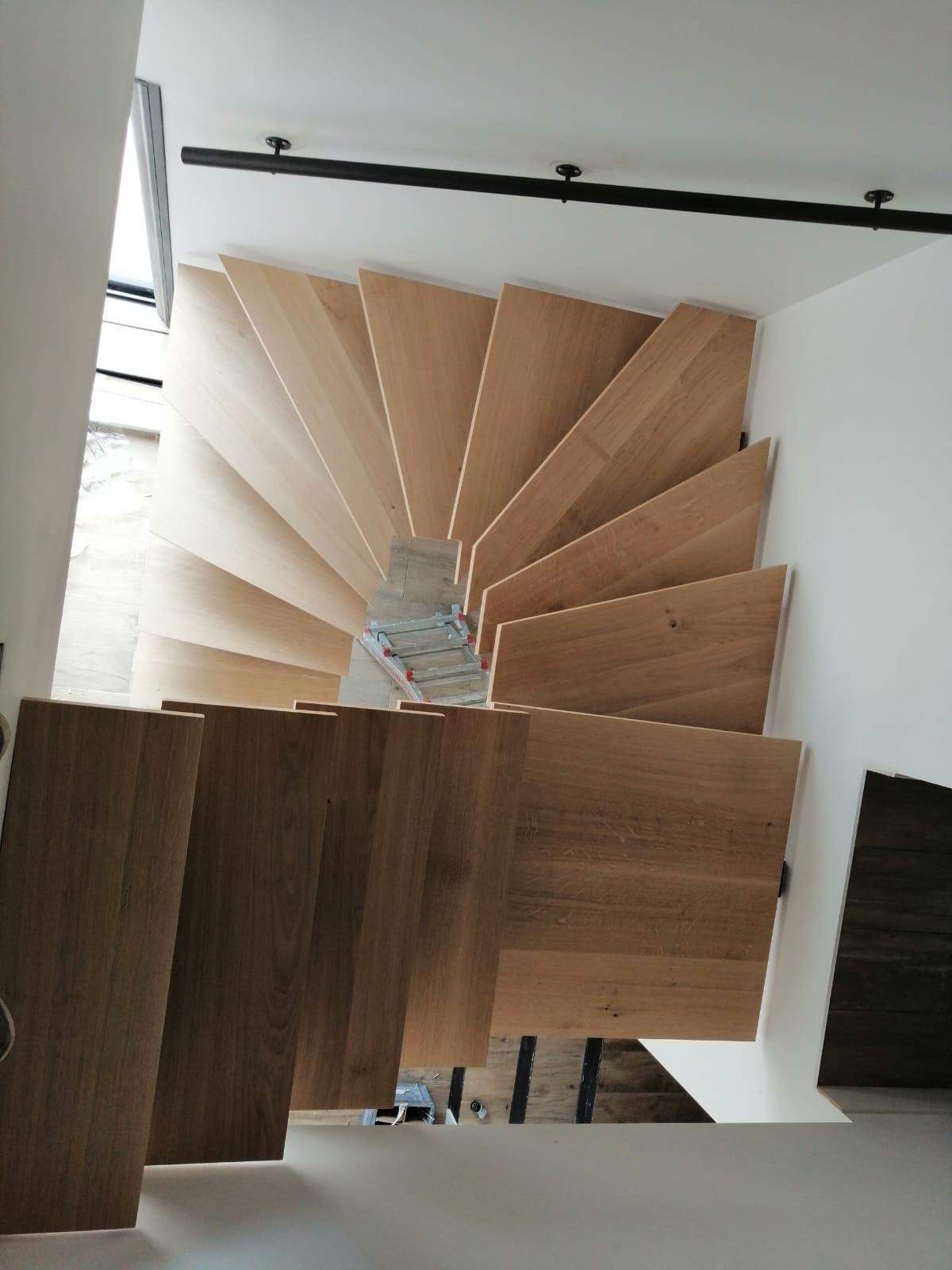Escalier en colimaçon en bois dans un intérieur lumineux, vu d'en bas.