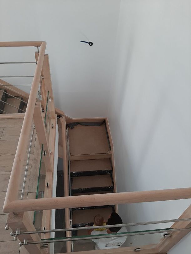 Escalier vu du dessus, un homme montant les marches avec un bébé dans les bras.