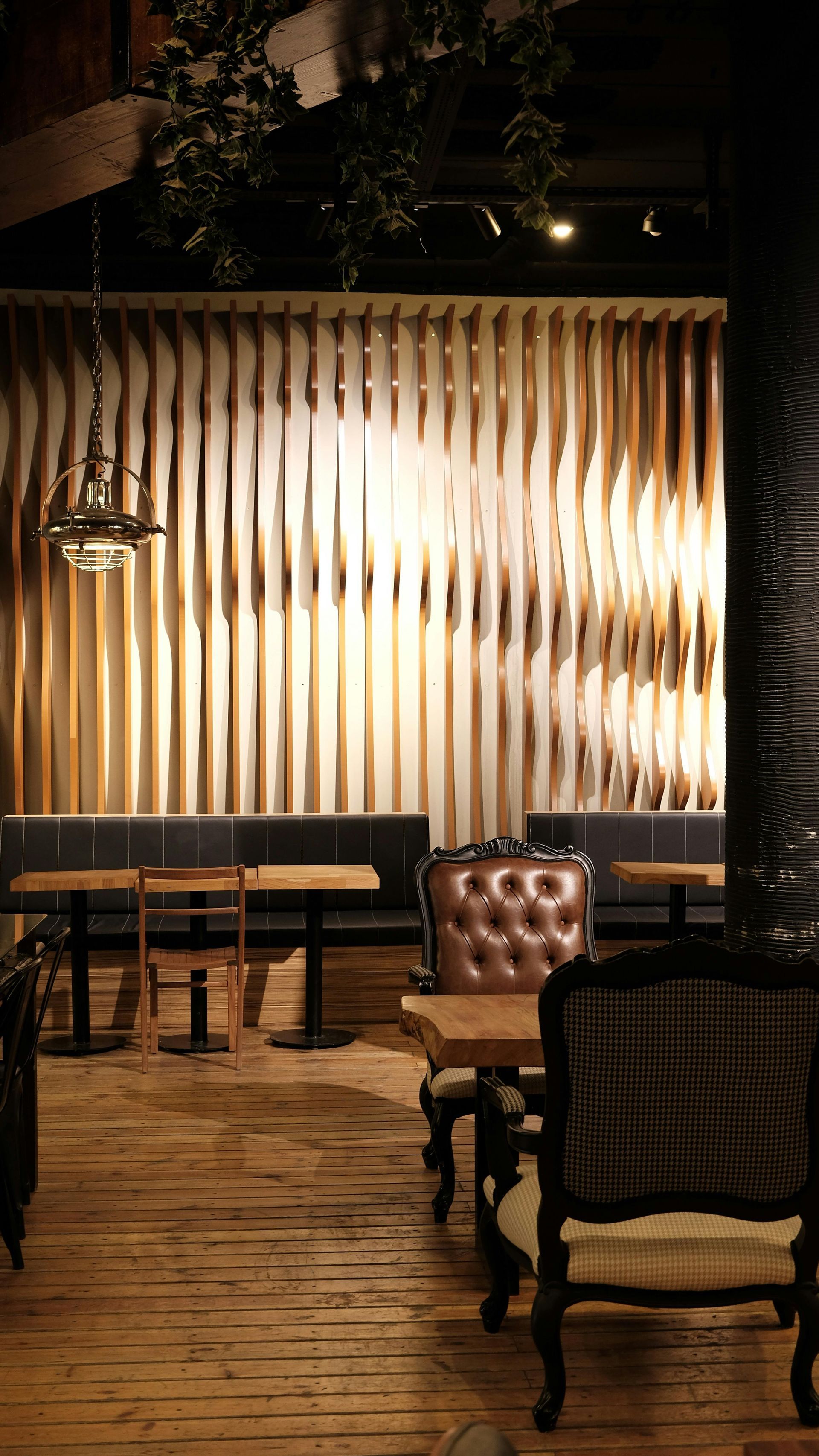 Salon moderne à l'éclairage tamisé, avec mur à rayures, parquet et chaises et tables capitonnées