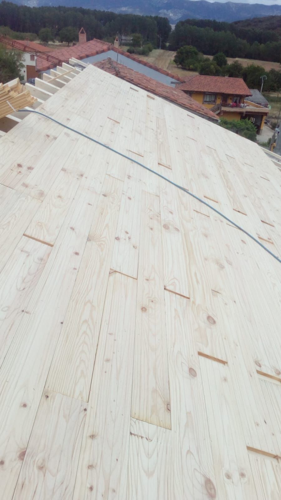 Se está construyendo un techo de madera con vista a las montañas al fondo.