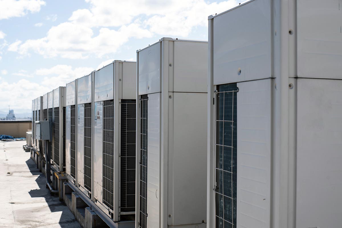 Plusieurs climatiseur VRF posés sur des  structures en bois sont alignés sur le toit d'un grand bâtiment