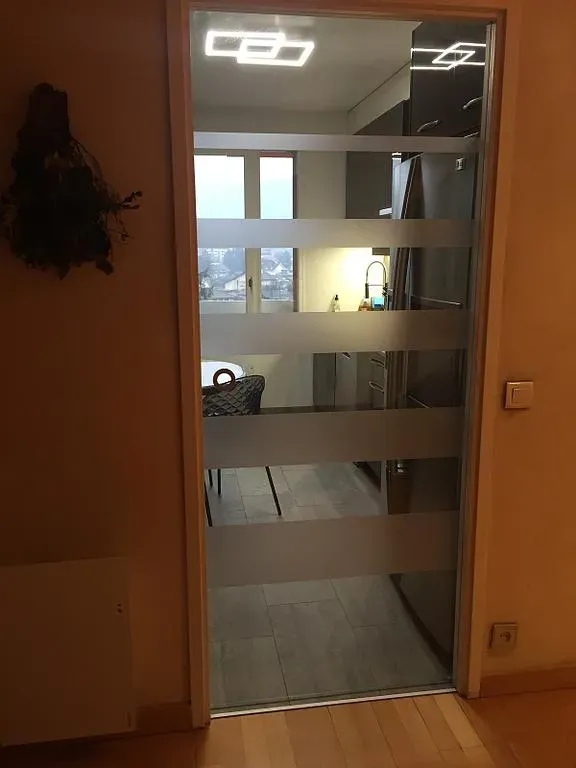 Porte vitrée avec des bandes opaques donnant sur une cuisine