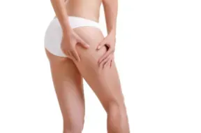 Mujer en ropa interior blanca pellizcando el muslo.