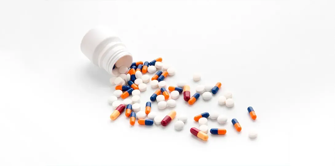 Un frasco de pastillas se vierte sobre una superficie blanca.
