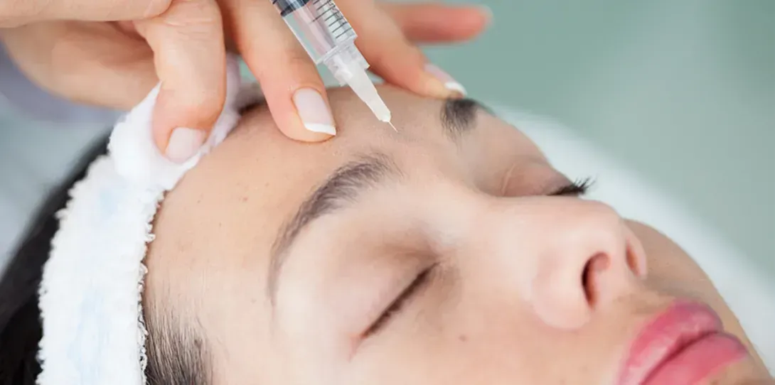 Una mujer recibe una inyección de botox en la frente.