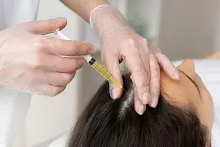 Una mujer recibe una inyección en el cabello.