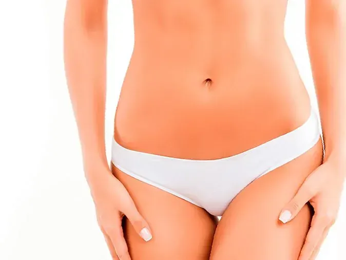 La mujer lleva ropa interior blanca y tiene las manos en las caderas.