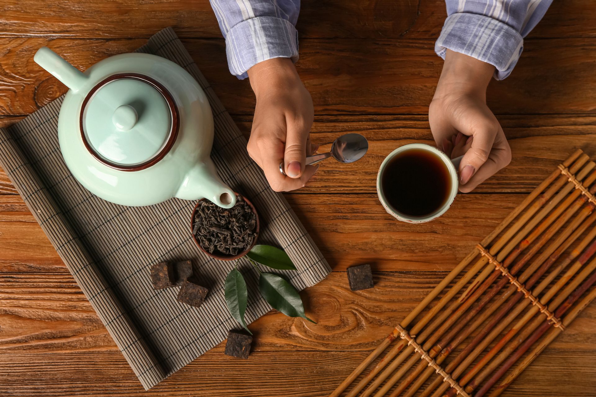 Una persona está sirviendo té en una taza sobre una mesa de madera.