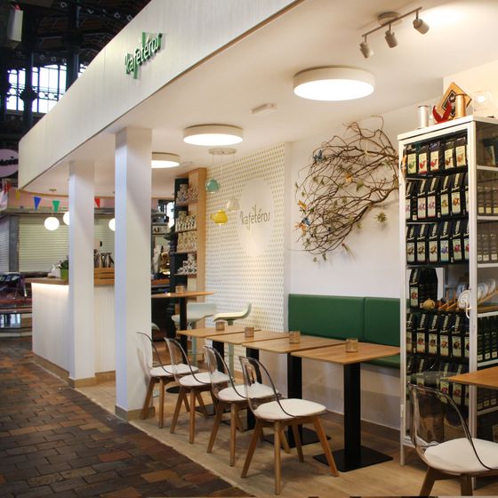 Una cafetería en un mercado con un mostrador y una máquina de café.