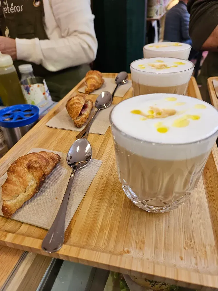 Una bandeja de madera con una taza de café y un croissant encima.