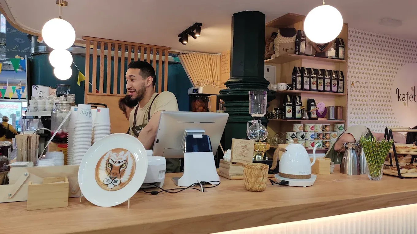 Un hombre está sentado en un mostrador en un restaurante hablando por un teléfono celular.
