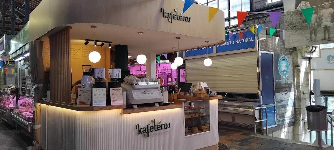 Una cafetería en un mercado con un mostrador y una máquina de café.