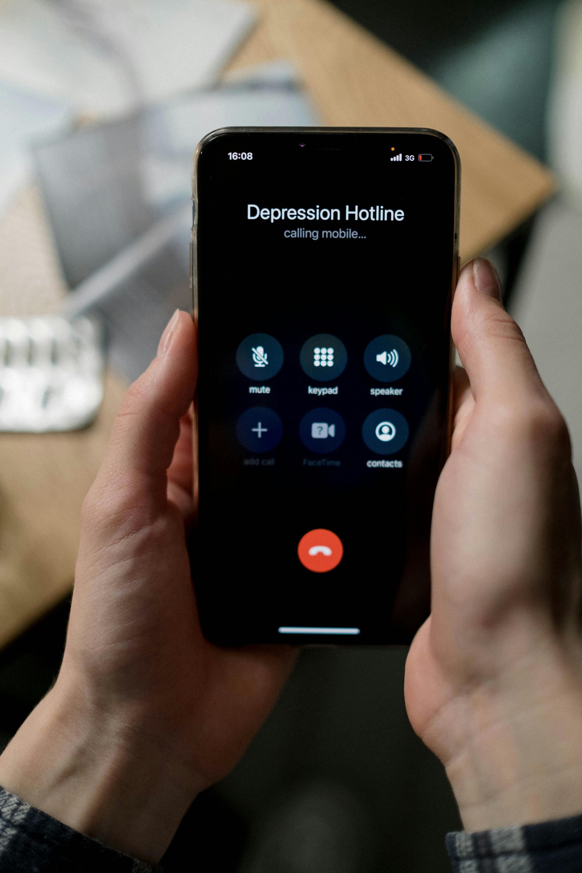Hände, die ein Smartphone halten, auf dem ein Anruf bei einer Depressions-Hotline angezeigt wird.