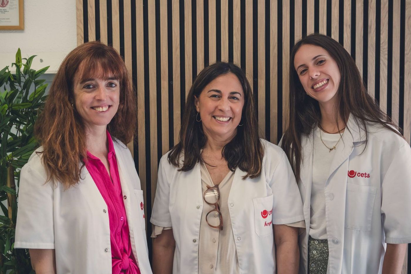 Tres mujeres con batas blancas posan para una fotografía.