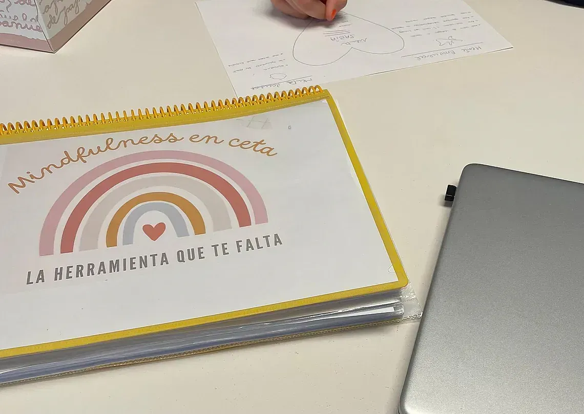 Una persona está escribiendo en un trozo de papel con un arcoíris encima.