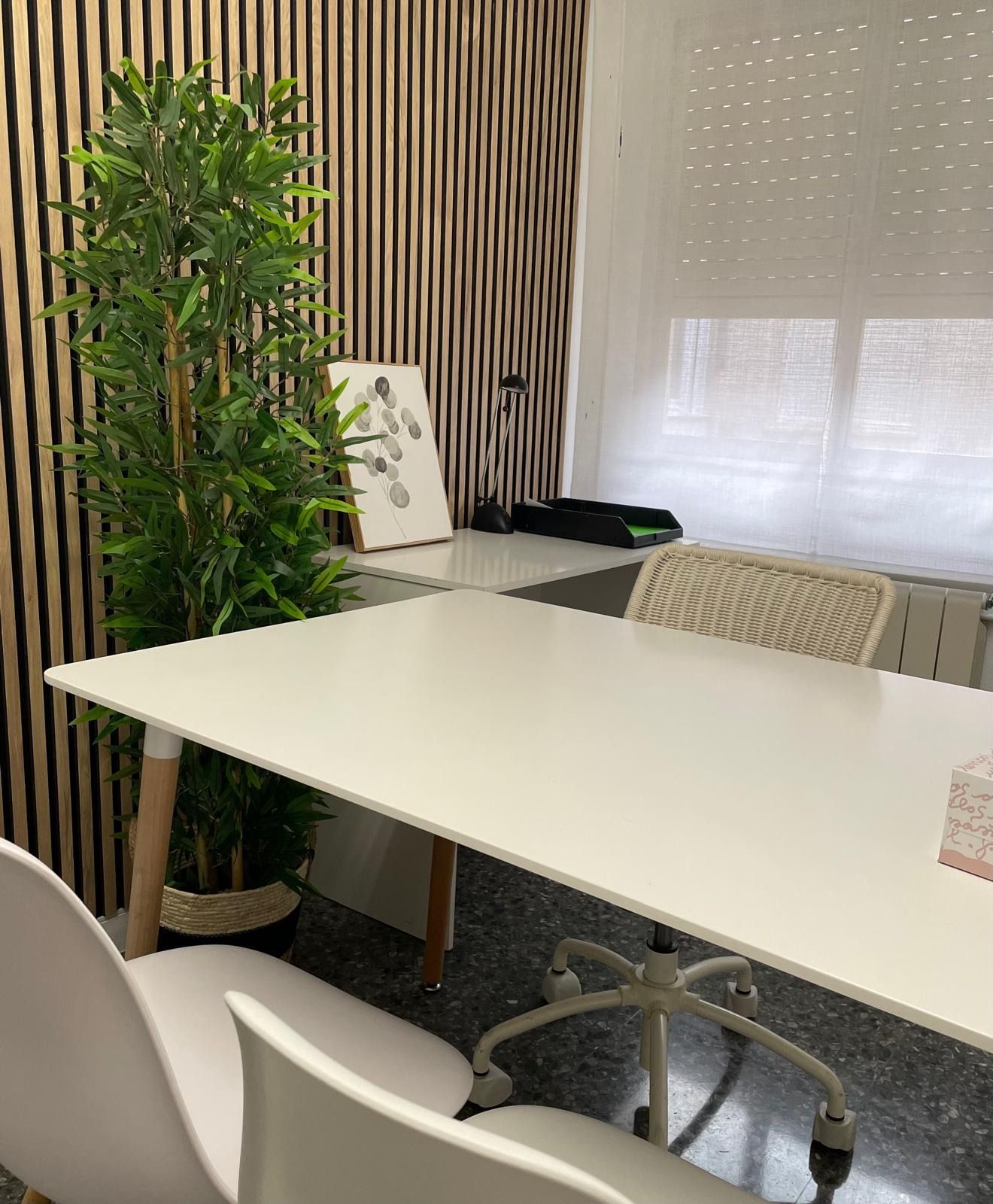 Una mesa blanca y sillas en una habitación con una planta en maceta.