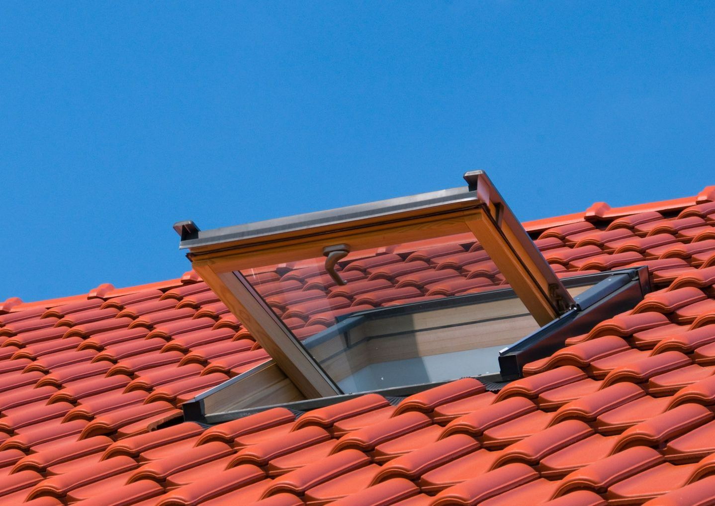 Une fenêtre de toit ouverte sur une toiture en tuile