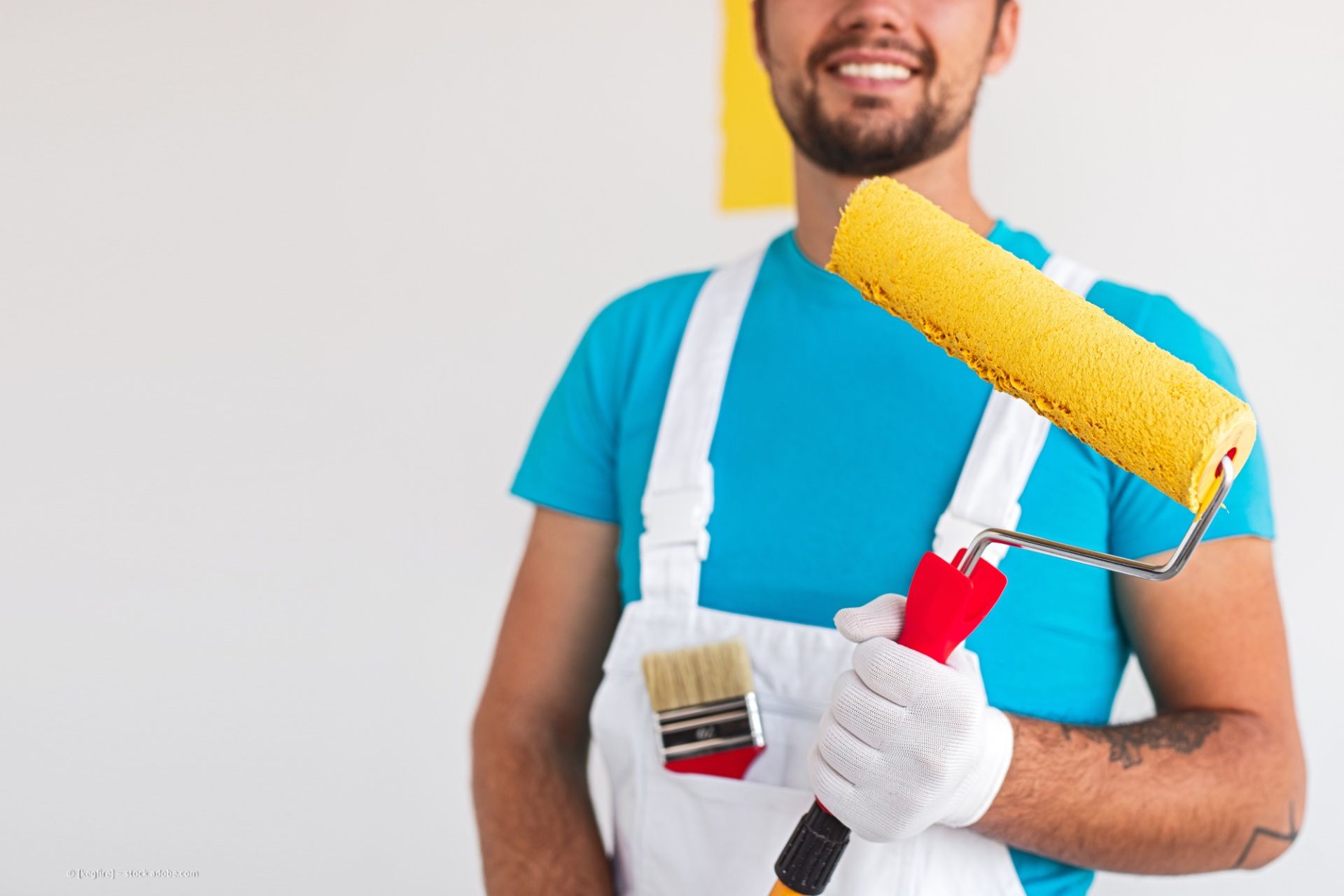 Malerbetrieb Thomas Beckstein – ein Maler im Blaumann und mit roter Mütze beim Streichen einer weißen Wand.