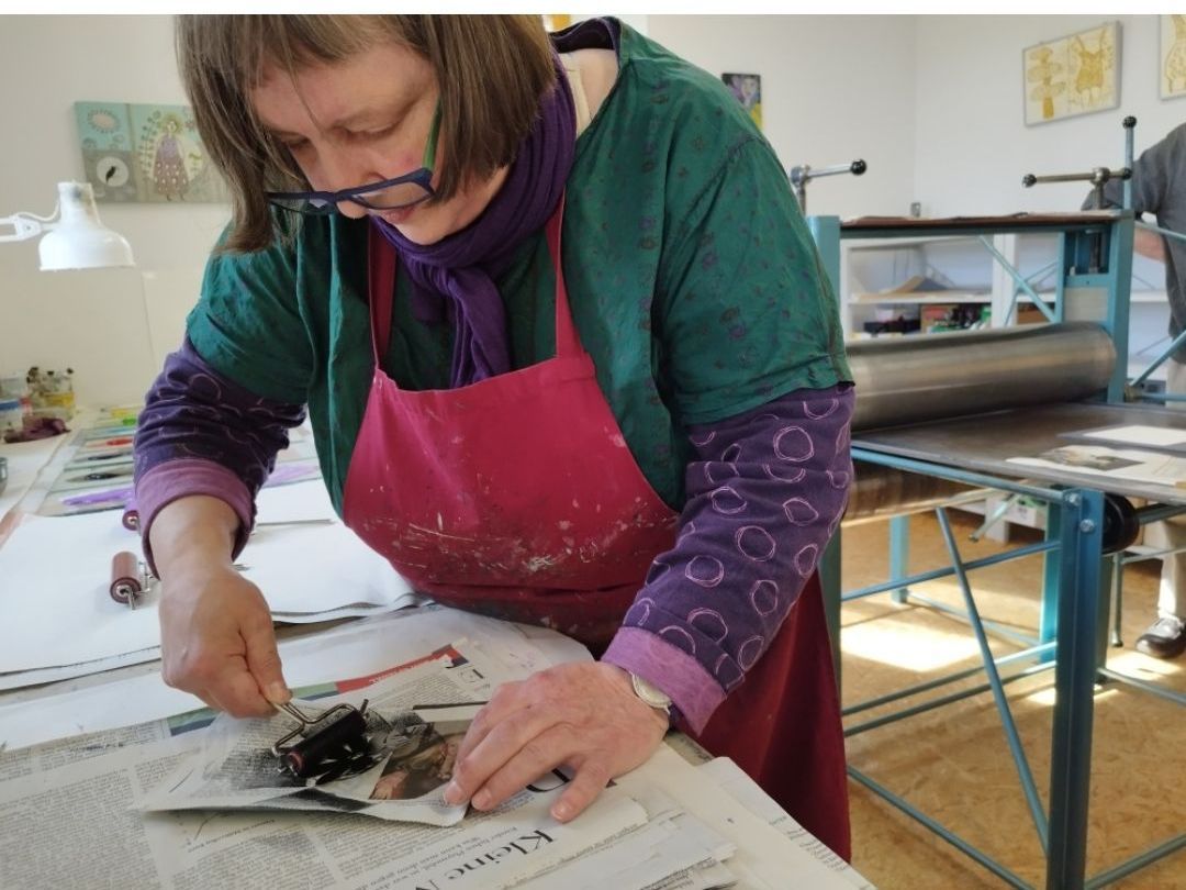 Eine Frau in einer Schürze arbeitet an einem Stück Papier