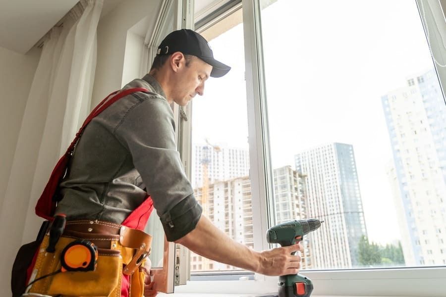 Un hombre está instalando una ventana con un taladro.