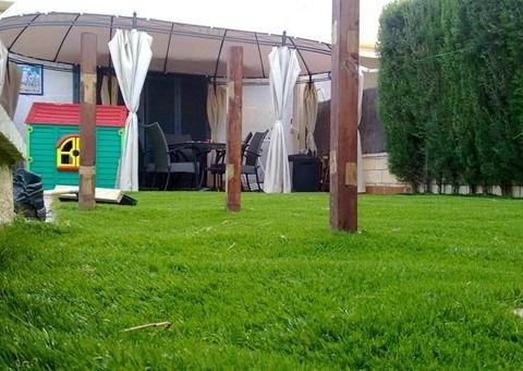 Un exuberante césped verde con un cenador al fondo.