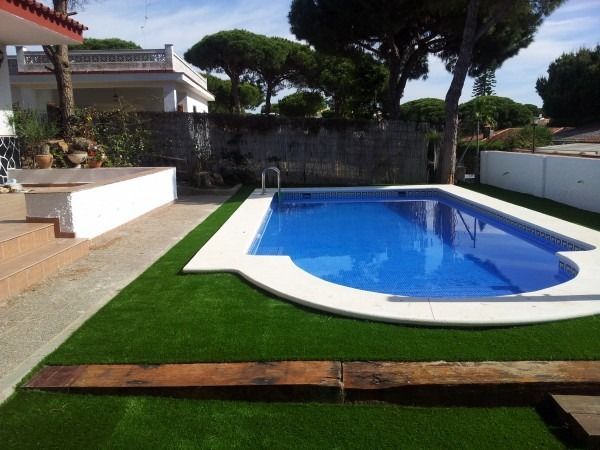 Una gran piscina está rodeada de un exuberante césped verde.