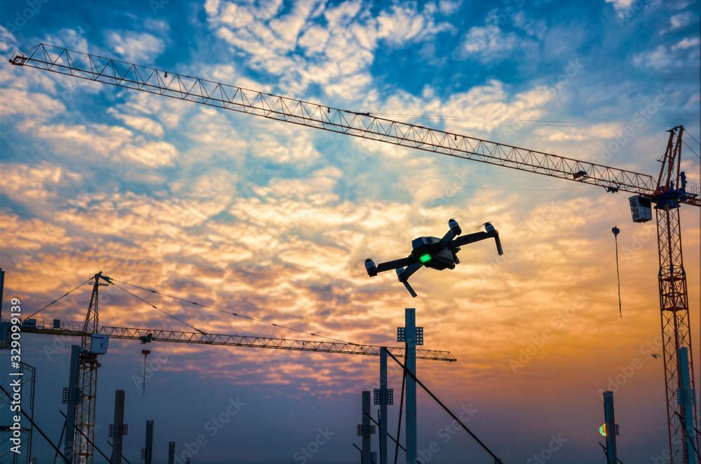 Un drone survole un chantier de construction au coucher du soleil.