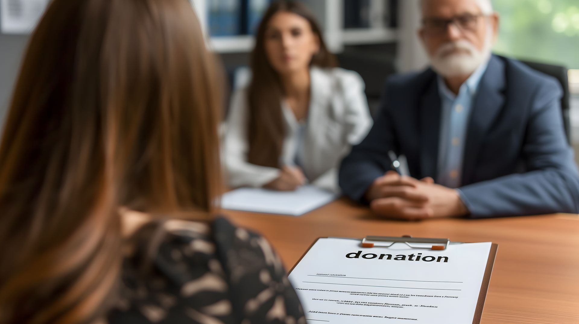 Une personne est assise en face d'un couple à une table ; un bloc-notes portant l'inscription DON est visible.